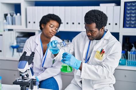 African American Man And Woman Scientists Measuring Liquid At