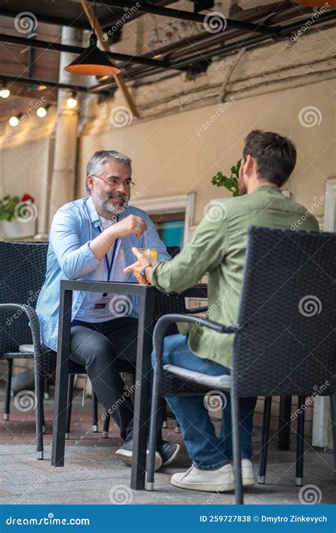 Two Men Sitting In The Cafe And Having An Interesting Conversation