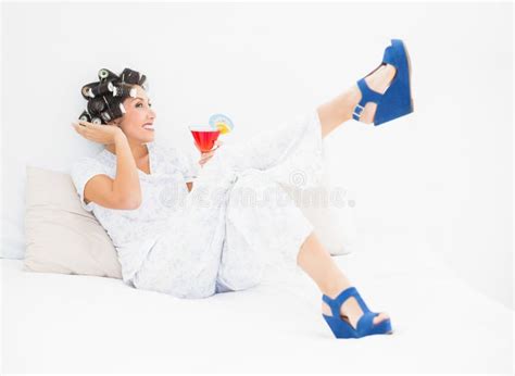 Brunette In Hair Rollers And Wedge Shoes Holding A Cocktail Stock Photo