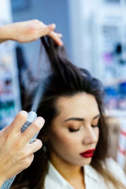 Premium Photo A Beautiful Brunette Woman Is Sprayed On Her Hair In A Beauty Salon