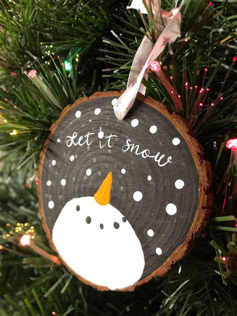 A Wooden Ornament Hanging On A Christmas Tree That Says Let It Snow