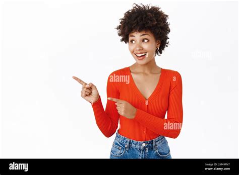 Smiling African American Woman In Stylish Outfit Pointing Finger Left Showing Promotion Text