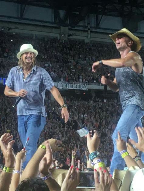 Two Men In Cowboy Hats And Jeans Are On Stage With Their Hands Up To