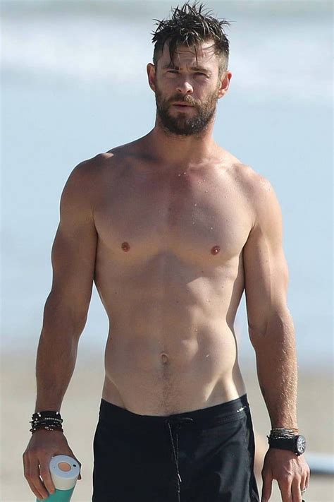 A Shirtless Man Walking On The Beach Holding A Frisbee In His Hand