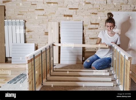 Front View Of A Young Blonde Girl Screwing A Screw With A Screwdriver In A Strip Of A Furniture