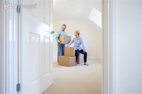 Senior Couple Downsizing In Retirement Carrying Boxes Into New Home On