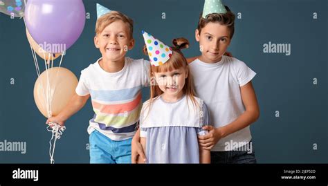 Cute Little Children In Birthday Hats And With Balloons On Color