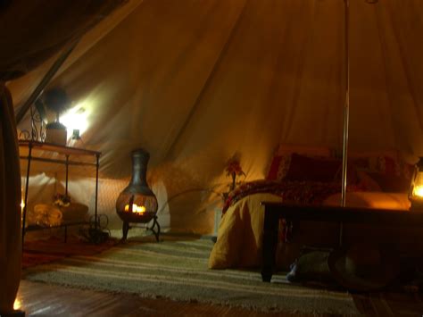 A Bed In A Tent With Two Lamps On Each Side And A Fire Place Next To It