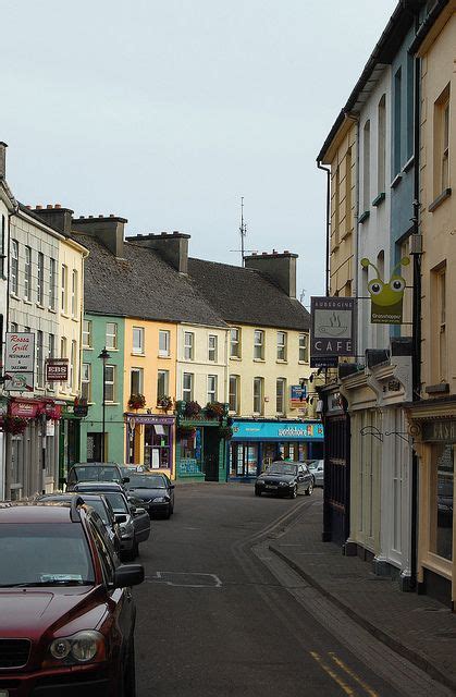 cars parked on the side of a street next to tall buildings with shops in them