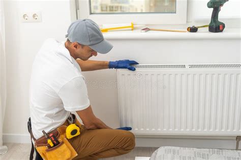 Um Encanador Macho Instala Um Radiador No Sistema De Aquecimento De Um