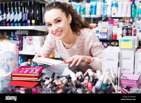 Portrait Of Positive Brunette Selecting Nail Polish In Beauty Store