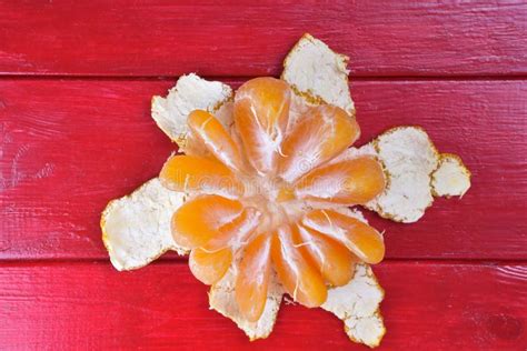 Una Mandarina A Medio Pelar Yace Sobre Un Fondo De Madera Roja En El