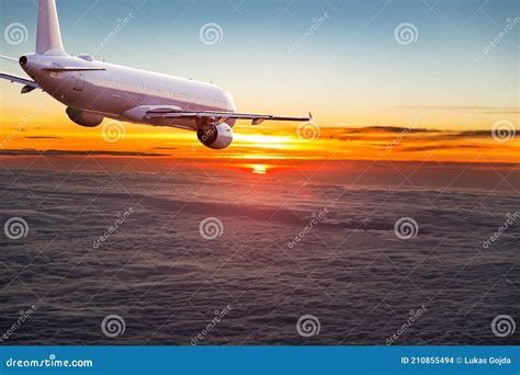 Commercial Airplane Jetliner Flying Above Dramatic Clouds Stock Photo