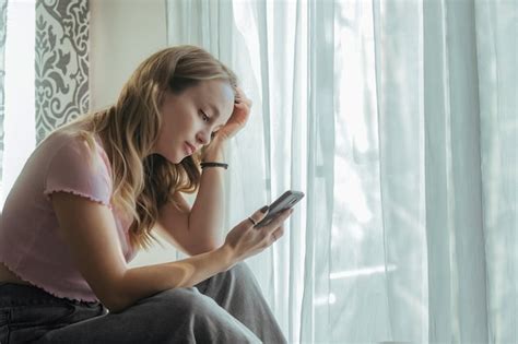 Premium Photo Sad Beautiful Girl Looking At Phone At Home