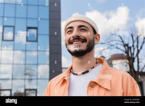 Portrait Of Positive And Stylish Gay Man Standing On Blurred Urban