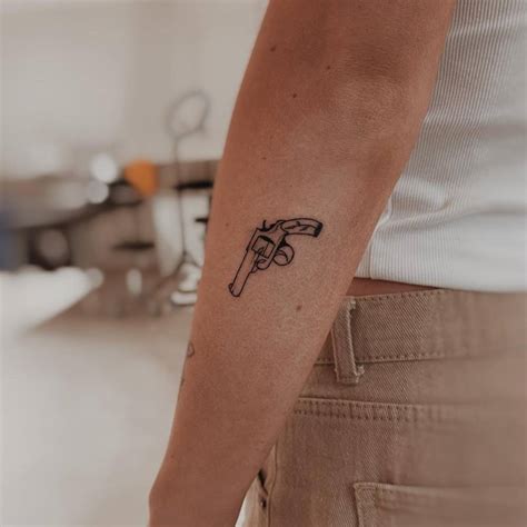 Tiny Revolver Tattoo Located On The Forearm