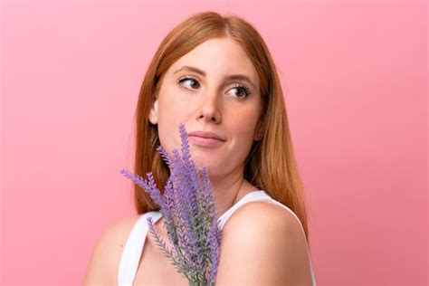 Mulher Jovem Ruiva Isolada Em Fundo Rosa Segurando Uma Planta De