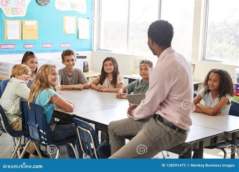 Male Teacher With Elementary School Kids In Class Discussion Stock