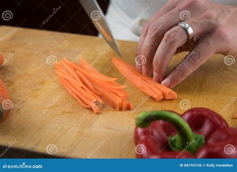 Sluit Omhoog Van Handen Snijdend Lange Stroken Van Wortelen Stock Foto