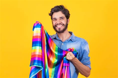 Homem gay feliz se divertindo segurando o símbolo da bandeira do arco