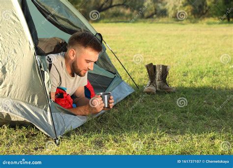 Young Man in Sleeping Bag with Cup of Drink Lying Inside Tent Stock ...