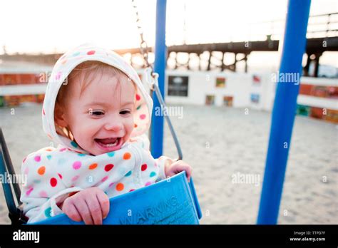 Happy baby girl swinging at playground Stock Photo - Alamy