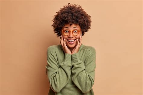 Free Photo Joyful Woman With Afro Hair Keeps Hands On Cheeks Smiles