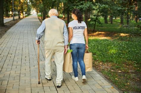 Premium Photo Cheerful Female Helping With Groceries For Old Man