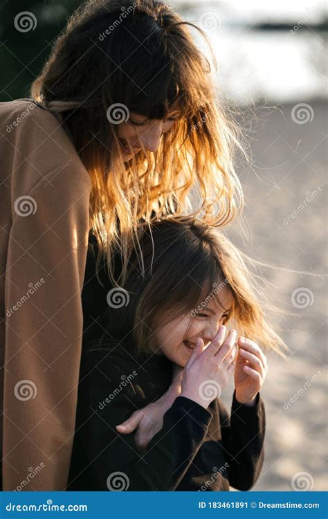 Loving Mother And Daughter Have Fun On The Beach At Sunset They Smile