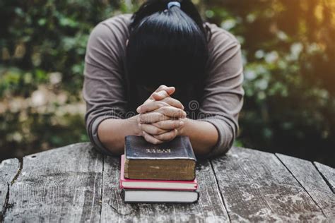 Hands Folded In Prayer On A Holy Bible In Church Concept For Faith