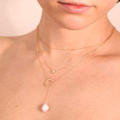 A White Woman Wears Three Gold Necklaces The Longest Is A Large Pearl