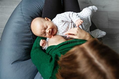 Newborn Crying Girl Baby Is Tired And Hungry In Arms Of Mother