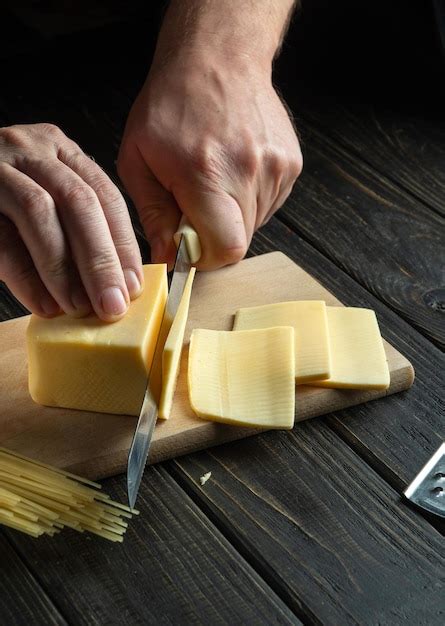 Premium Photo The Cook Hands With Knife Cutting A Cheese On The