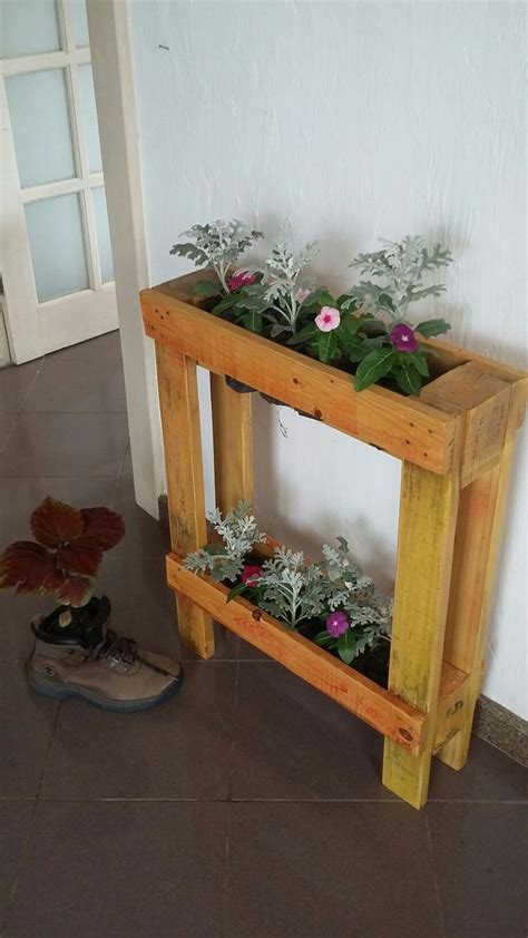 A Wooden Planter With Flowers In It Next To A Pair Of Shoes On The Floor