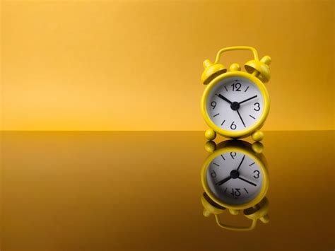 Premium Photo Yellow Alarm Clock On Yellow Background With Reflection