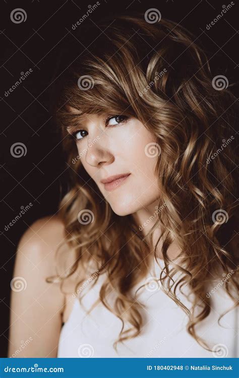 Portrait Of A 36 Year Old Woman With Curly Hair And Brown Slanting Eyes