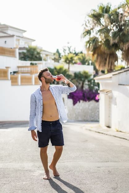 Um Homem De Camisa Listrada Caminha Pelas Ruas De Uma Pequena Cidade