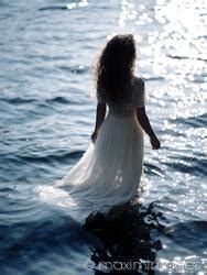 Photo Of Woman In Sheer White Dress Standing In The Water In Sunshine