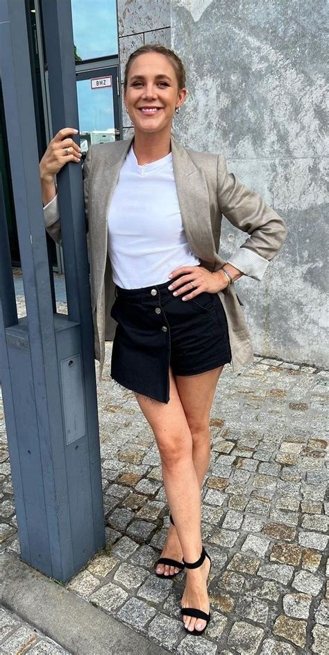 A Woman Standing Next To A Metal Pole On A Brick Sidewalk With Her