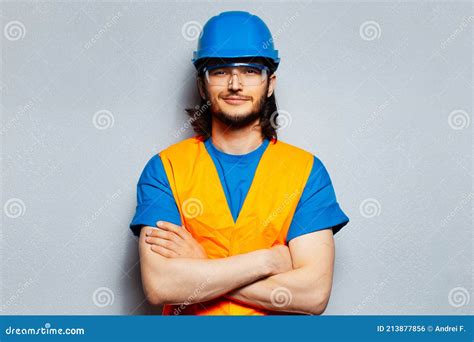 Studio Portrait Of Young Smiling Man With Crossed Arms Construction