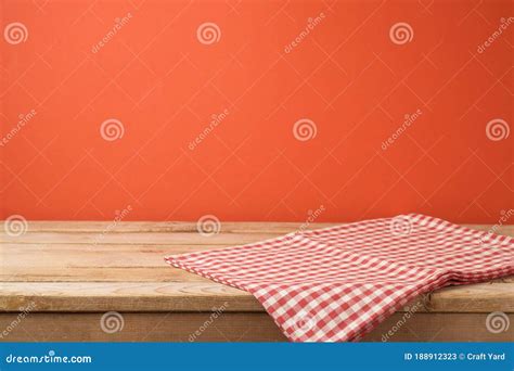 Empty Wooden Table With Red Checked Tablecloth Over Red Wall Background