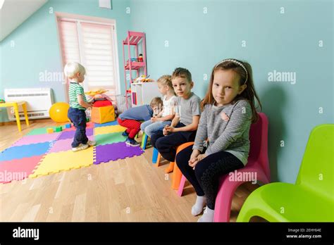 Children are sitting on the colorful chairs in the kindergarten Stock