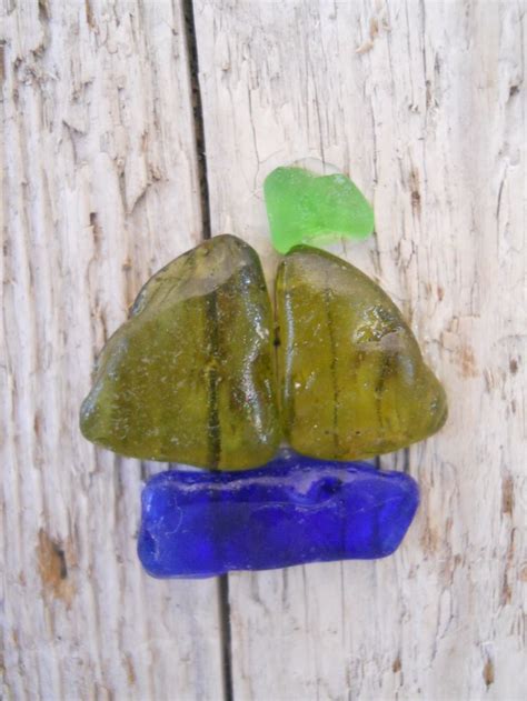 Two Pieces Of Glass Sitting On Top Of A Piece Of Wood Next To A Green Leaf