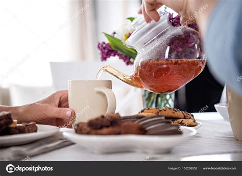 Man Pouring Tea Into Cup During Breakfast Stock Photo