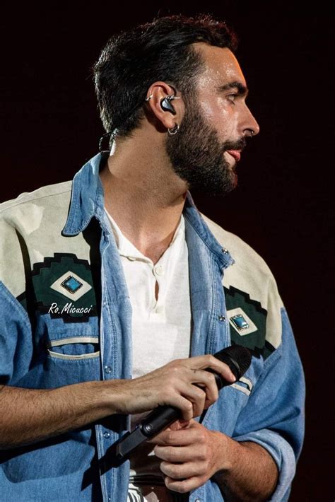 A Man With Ear Buds On His Ears Is Standing In Front Of A Dark Background