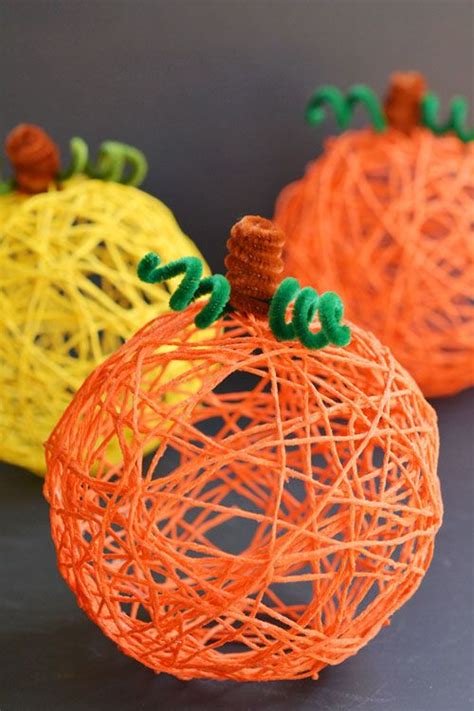 Three Orange And Yellow Yarn Pumpkins Sitting On Top Of A Black Surface