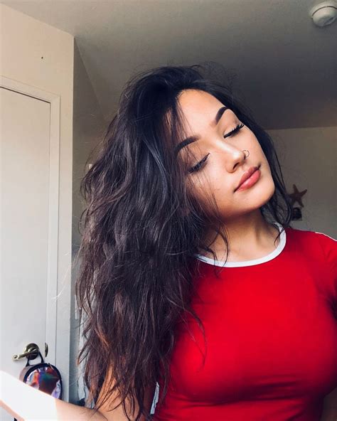 A Woman In A Red Shirt Is Brushing Her Long Dark Hair With An Electric