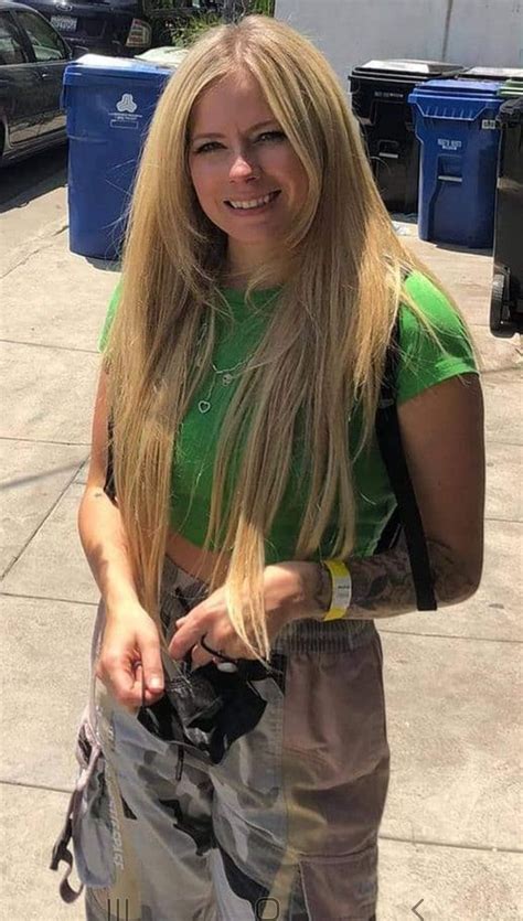 A Woman With Long Blonde Hair Standing On The Sidewalk