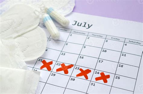 Menstrual Pads And Tampons On Menstruation Period Calendar With Red Cross Marks Lies On Lilac