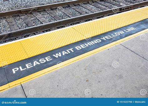 Train Platform with Sign Please Wait Behind the Yellow Line and Yellow ...